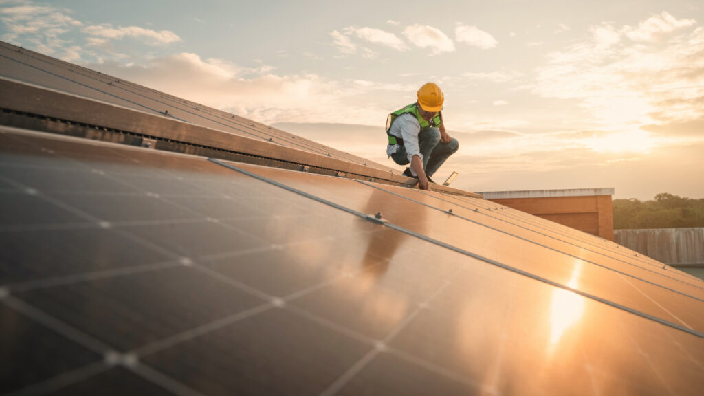handwerker montiert eine photovoltaikanlage auf dem dach eines hauses während die sonne sich in den solarplatten spiegelt